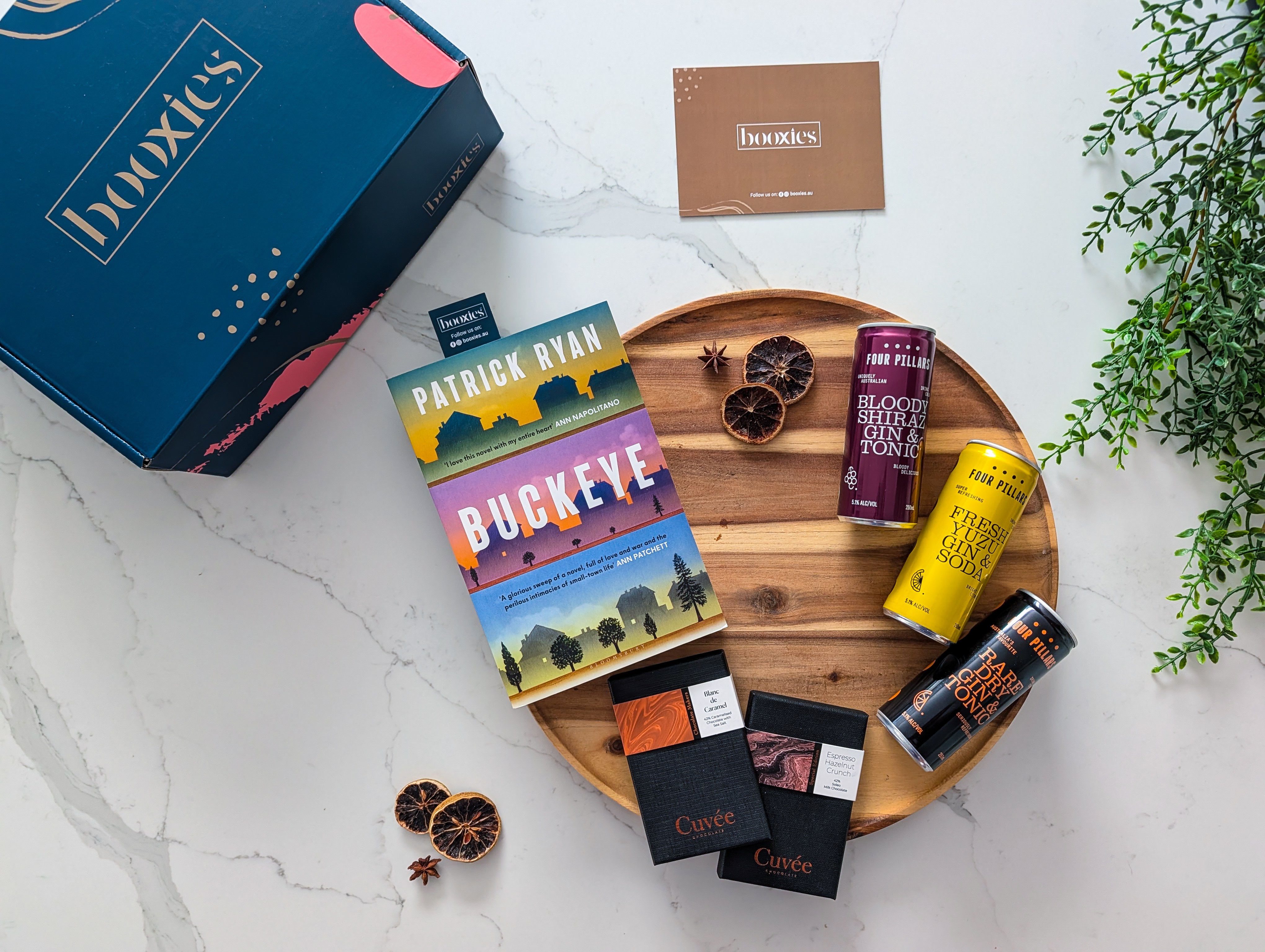 Buckeye book on a wooden tray with 2 hand made chocolate from Cuvee and 3x g&T from Four Pilars and a booxies box making G&T Trio n Tale Curated Booxies