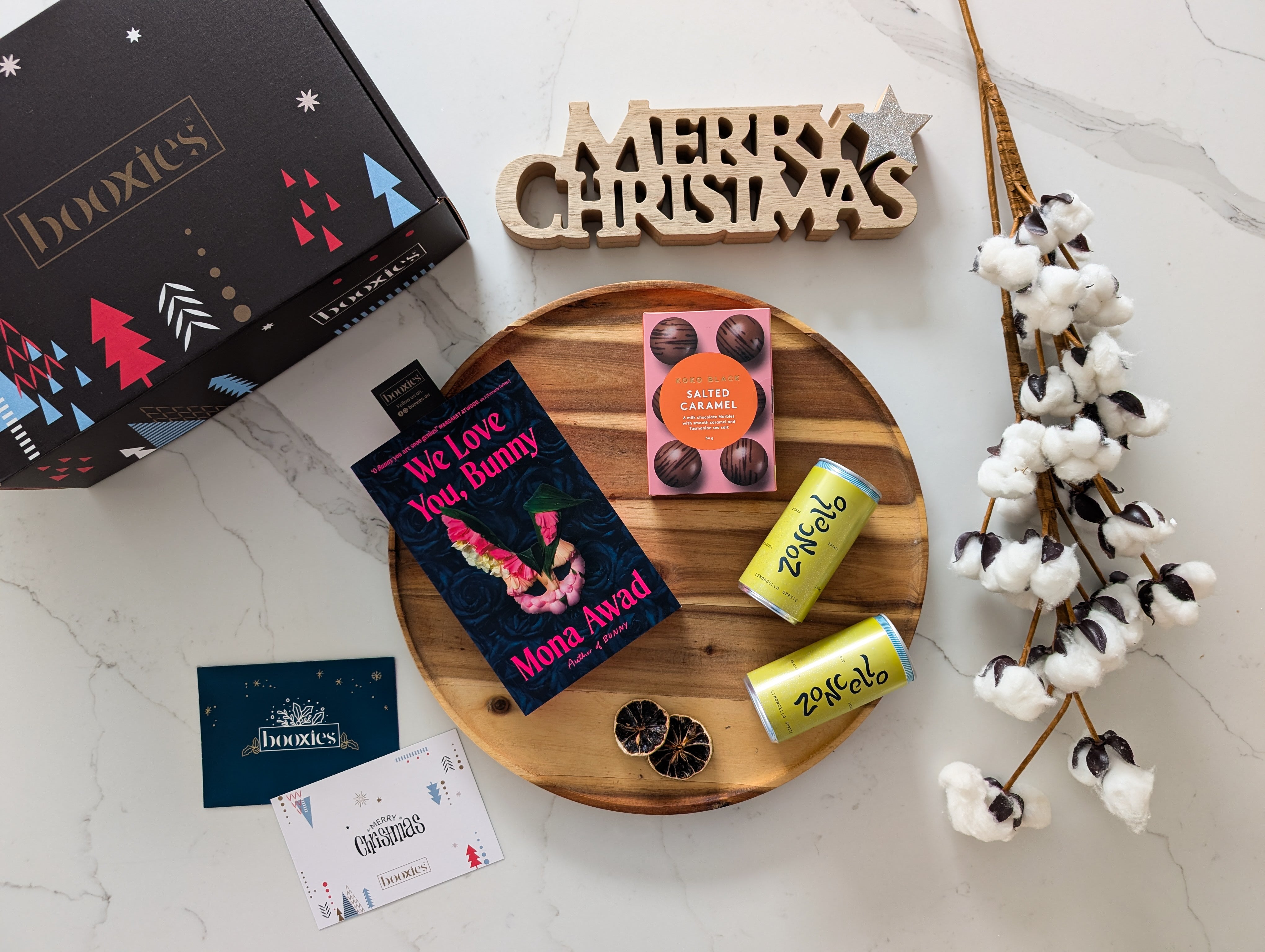 Christmas-themed items including a box, books, and cans on a marble surface with decorative elements.
