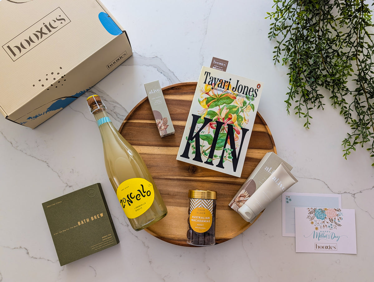 Assorted items including a bottle of limoncello from Zonzo, book, and box on a marble surface with a plant in the background.