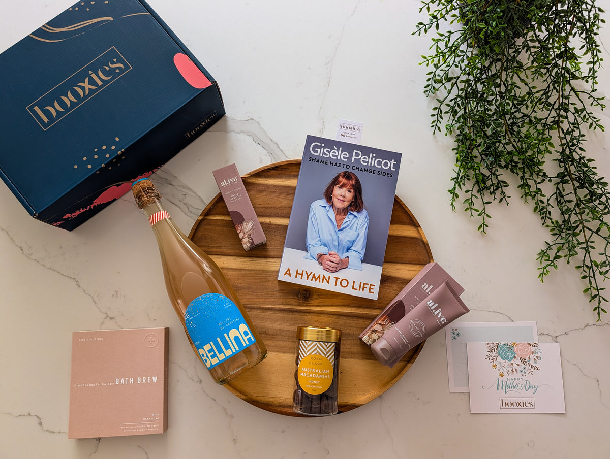 Gesille Pelicot book, bottle of bellina, and other items on a wooden tray with 'buxies' box. for Mum's Unwind Retreat mother's day gift box