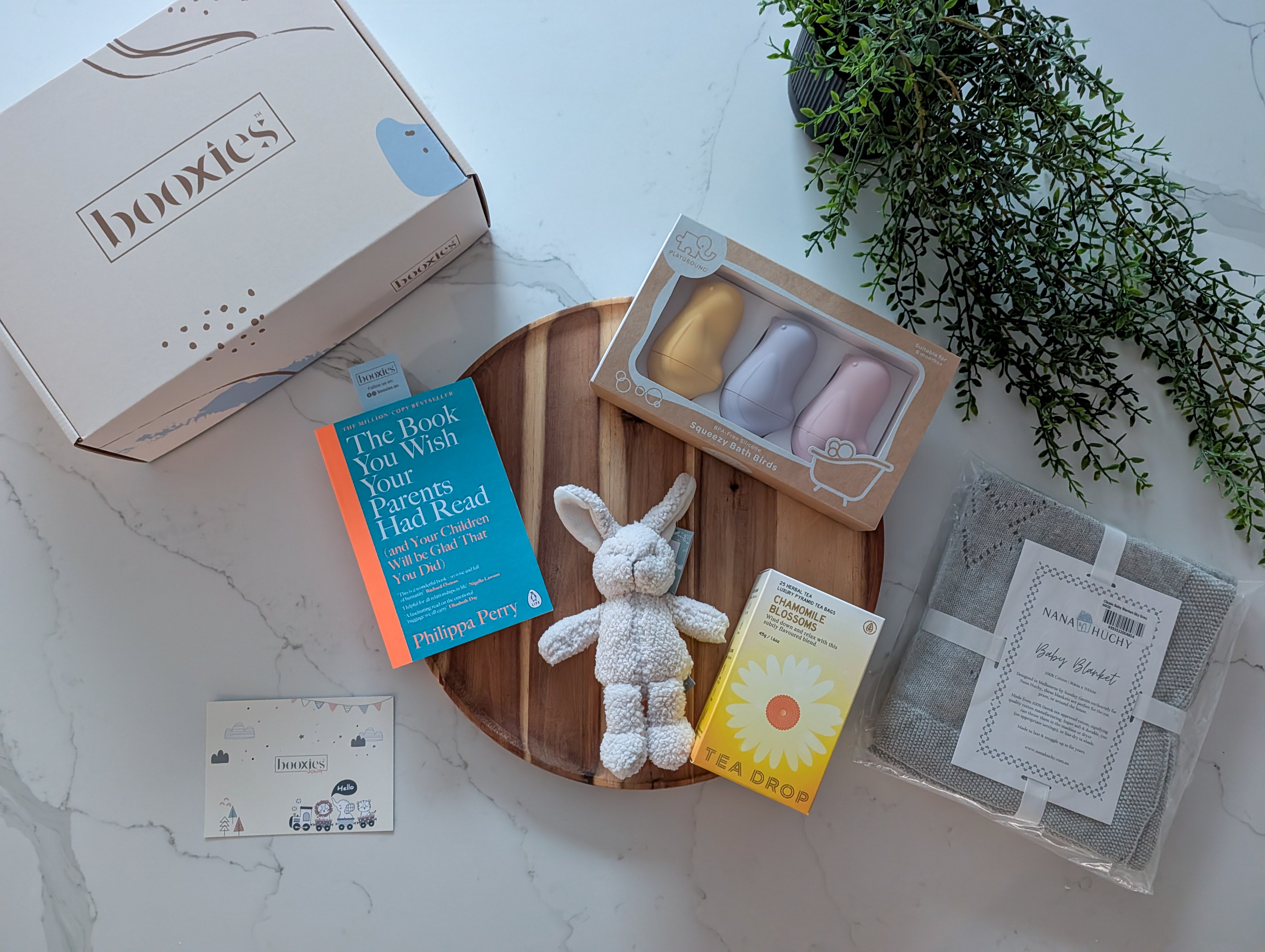 Gifting set with books, a plush toy, and tea bags on a white surface.