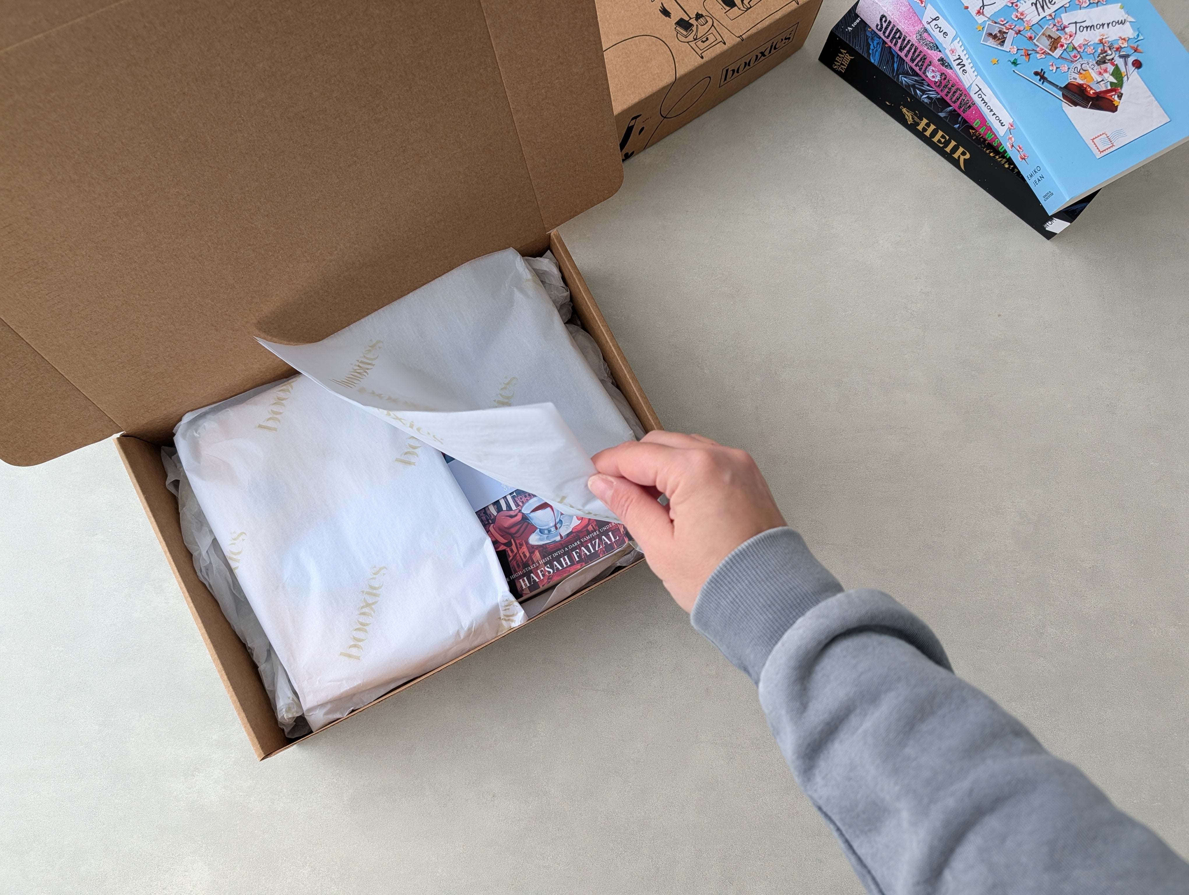sneak peak into Booxies YA blind date showing a hand holding the tissue paper in the kraft box