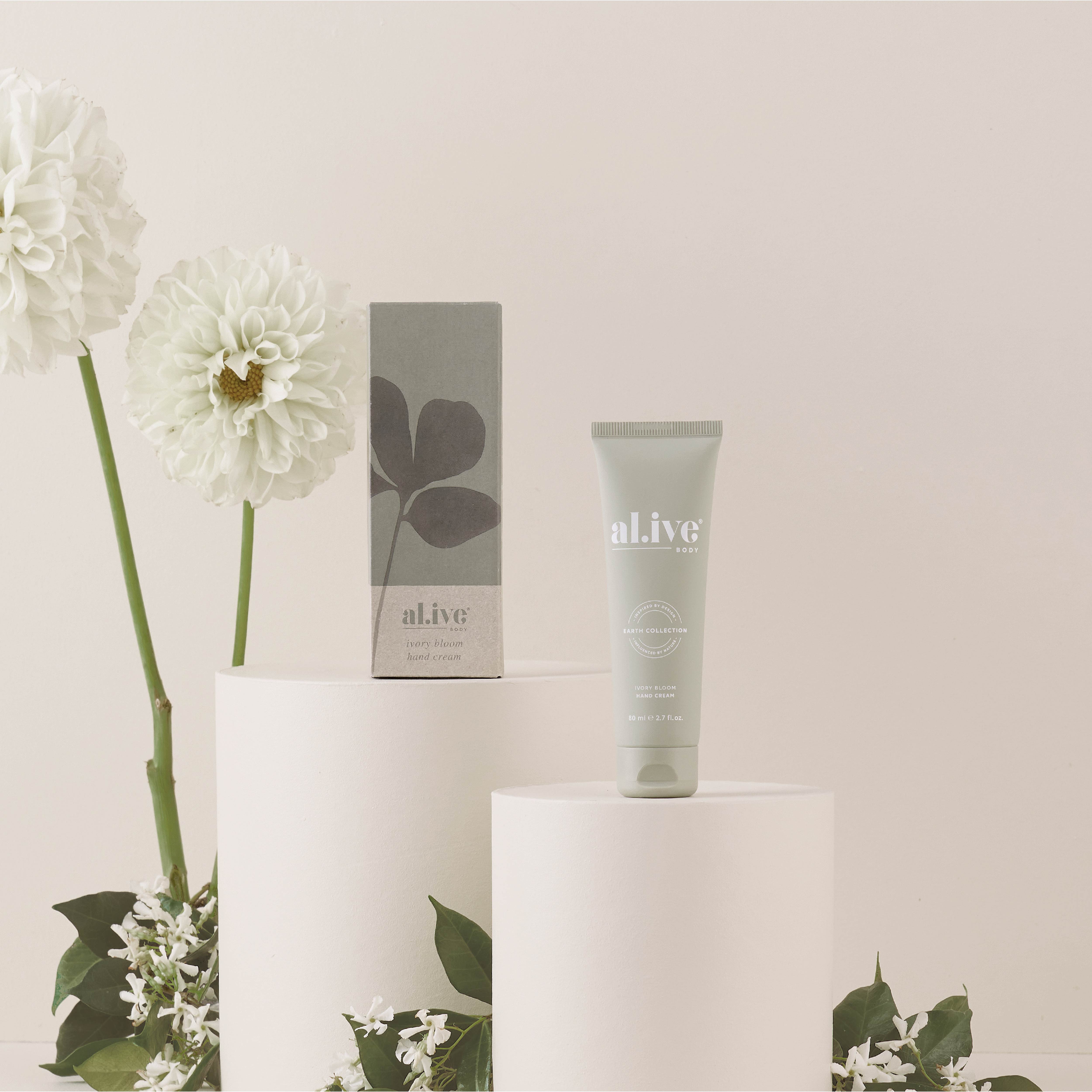 Tube of 'alive' cream on a white pedestal with flowers and a box in the background